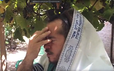 A man in a tallit is holding his head
