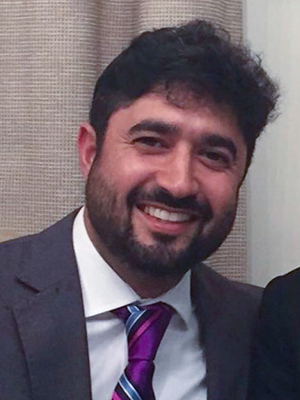 A man in a suit and tie smiling for the camera.