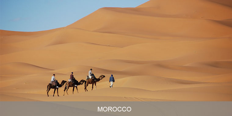 Three people riding on horseback in the desert.
