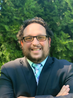 A man in a suit and tie smiling for the camera.