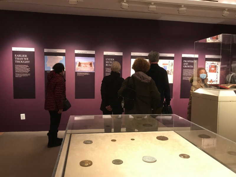 A group of people standing around looking at some coins.