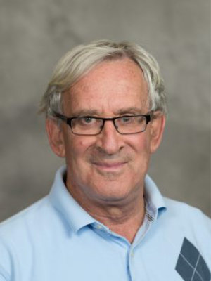 A man with glasses and white hair wearing a blue shirt.